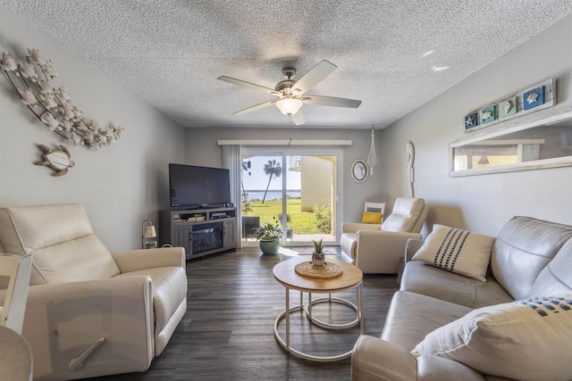 living room featuring a textured ceiling, ceiling fan, and dark wood-type flooring