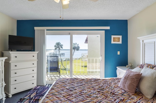 carpeted bedroom featuring ceiling fan, a water view, a textured ceiling, and access to outside