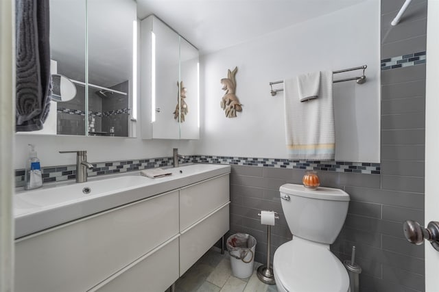 bathroom featuring tile patterned flooring, vanity, toilet, and tile walls