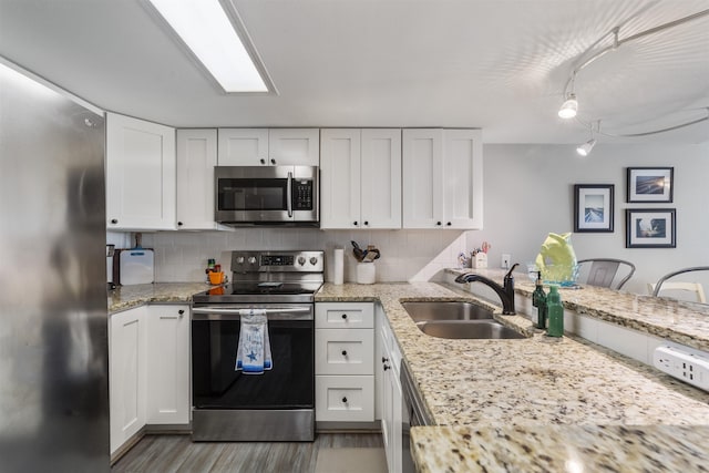 kitchen with white cabinets, backsplash, stainless steel appliances, and sink