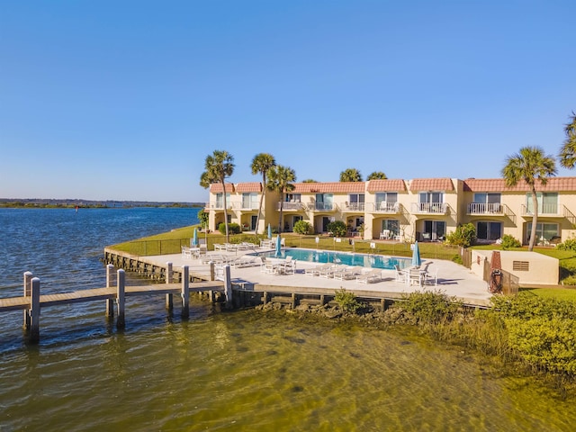 dock area featuring a community pool, a water view, and a patio