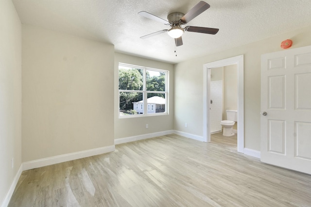 641 W Cathedral, Saint Augustine, FL 32084 - unfurnished bedroom featuring a textured ceiling, connected bathroom, light wood-type flooring, and baseboards