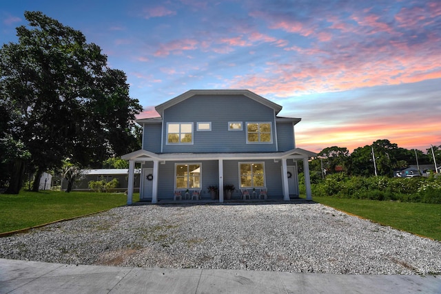 view of front facade featuring covered porch, driveway, and a front lawn