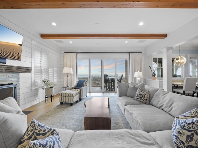 living room featuring a chandelier, beam ceiling, a wealth of natural light, and light hardwood / wood-style flooring