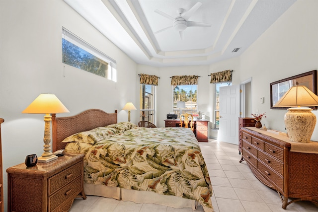 bedroom featuring a raised ceiling, light tile patterned floors, and ceiling fan