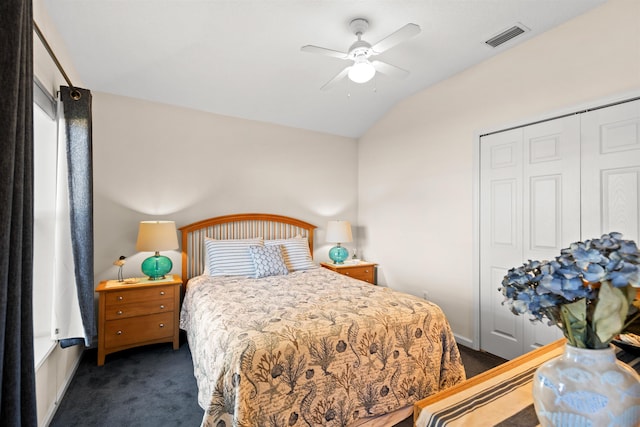 bedroom featuring dark carpet, vaulted ceiling, a closet, and ceiling fan