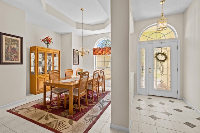 dining area featuring a notable chandelier, a towering ceiling, a raised ceiling, and light tile patterned flooring