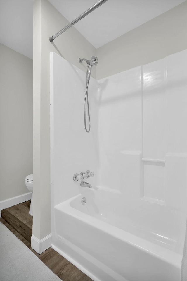 bathroom featuring hardwood / wood-style floors, bathing tub / shower combination, and toilet