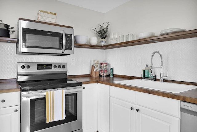 kitchen with tasteful backsplash, stainless steel appliances, sink, and white cabinets