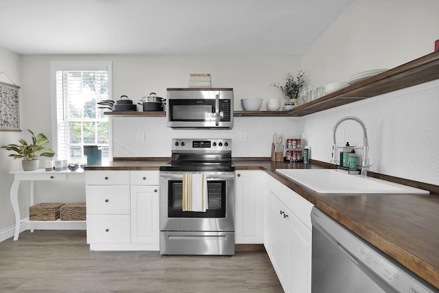 kitchen with sink, light hardwood / wood-style flooring, white cabinets, and appliances with stainless steel finishes