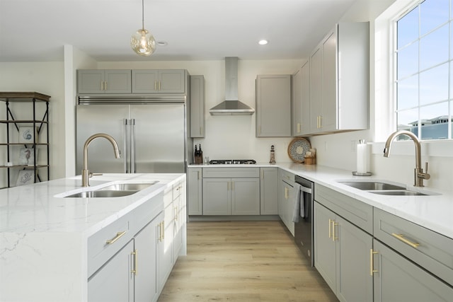 kitchen featuring decorative light fixtures, sink, stainless steel appliances, and wall chimney range hood