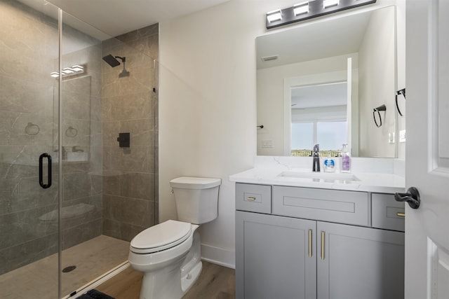 bathroom featuring vanity, toilet, wood-type flooring, and walk in shower