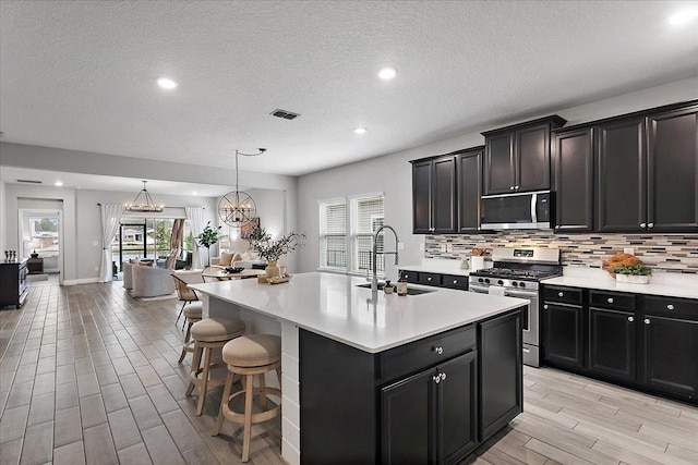 kitchen with visible vents, a sink, light countertops, appliances with stainless steel finishes, and tasteful backsplash