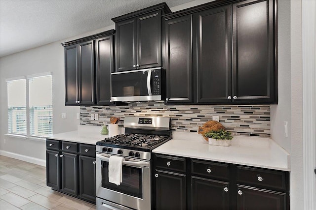 kitchen featuring tasteful backsplash, appliances with stainless steel finishes, and dark cabinets