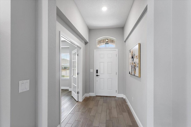 doorway featuring baseboards, a textured ceiling, and wood finished floors