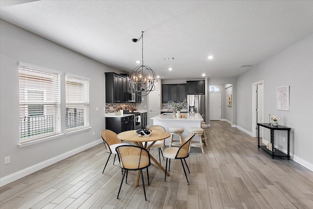 dining area featuring recessed lighting, light wood-style flooring, a textured ceiling, and baseboards