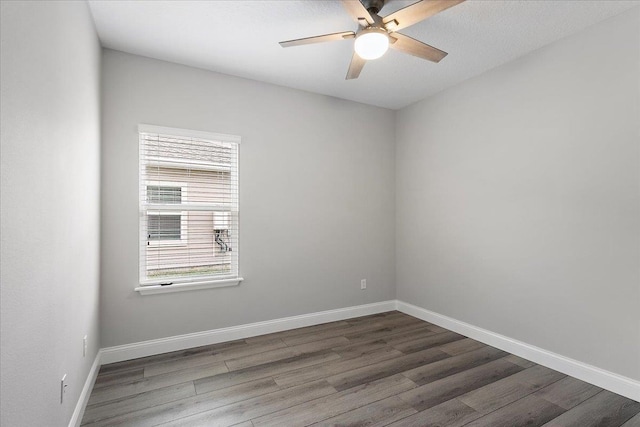 unfurnished room featuring baseboards, dark wood-style floors, and a ceiling fan