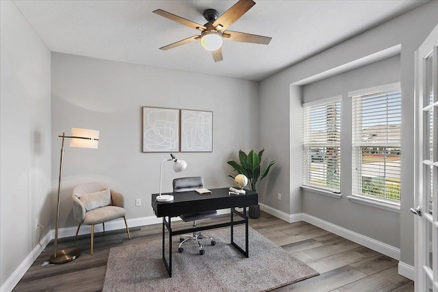 office space featuring baseboards, wood finished floors, and a ceiling fan