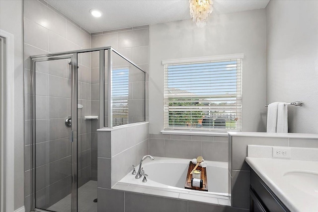 full bath with vanity, a shower stall, a garden tub, and a textured ceiling