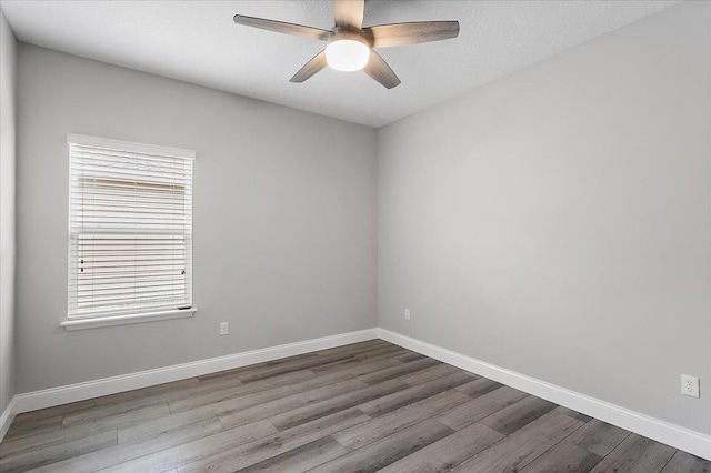 empty room featuring a textured ceiling, a ceiling fan, baseboards, and wood finished floors