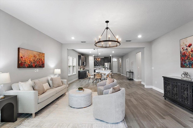 living room featuring visible vents, a notable chandelier, wood finished floors, recessed lighting, and baseboards