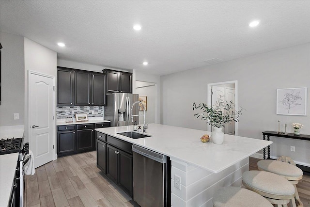 kitchen featuring backsplash, appliances with stainless steel finishes, light countertops, and a sink