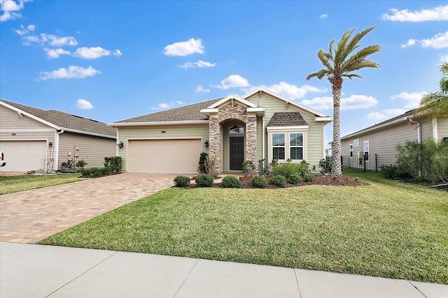 view of front of home with decorative driveway, stone siding, fence, a front yard, and a garage