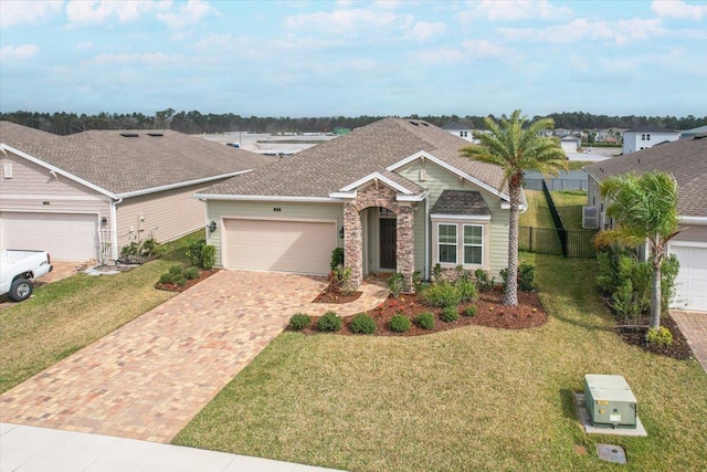 view of front facade featuring a front lawn, fence, decorative driveway, a garage, and stone siding