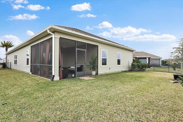 rear view of house with a sunroom, a lawn, and fence