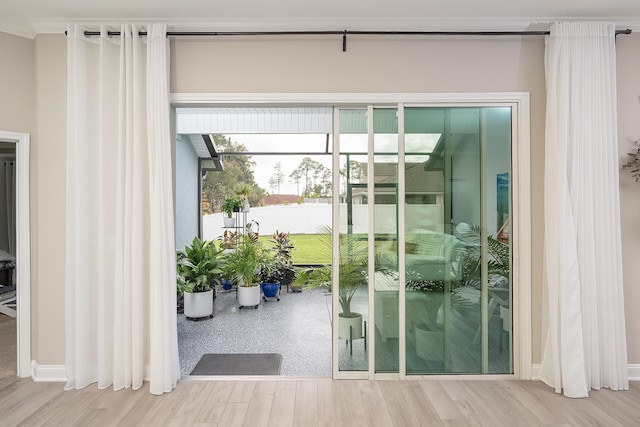 doorway to outside with a healthy amount of sunlight, ornamental molding, and wood finished floors