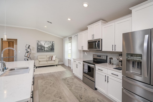 kitchen featuring a sink, visible vents, vaulted ceiling, light countertops, and appliances with stainless steel finishes