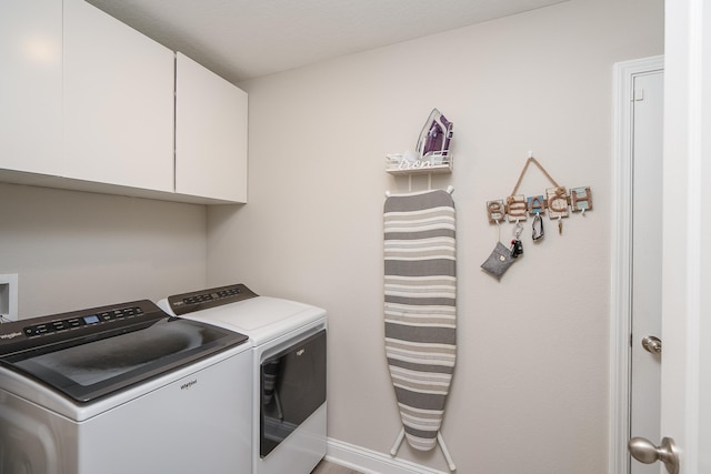 laundry room featuring washing machine and dryer, cabinet space, and baseboards