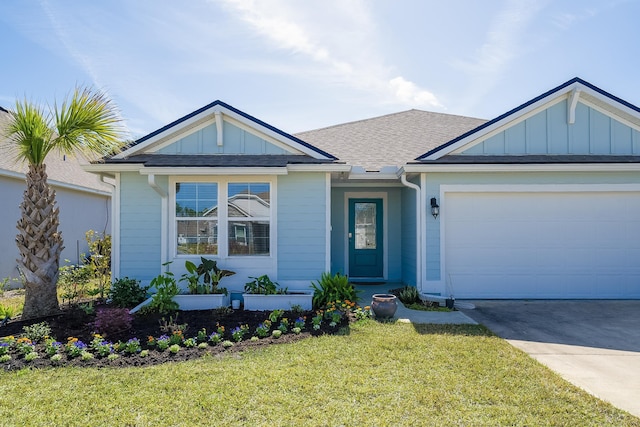 view of front facade featuring a garage, concrete driveway, roof with shingles, board and batten siding, and a front yard