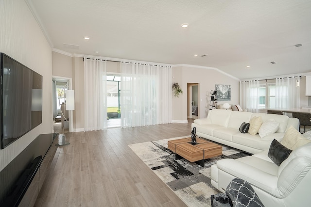 living area with lofted ceiling, crown molding, baseboards, and wood finished floors