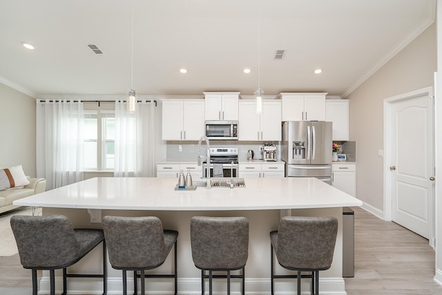 kitchen featuring stainless steel appliances, visible vents, ornamental molding, decorative backsplash, and a kitchen bar