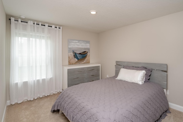 carpeted bedroom featuring a textured ceiling and baseboards