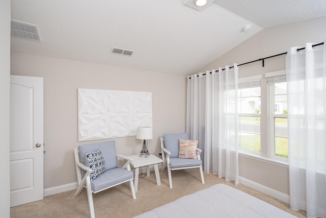 sitting room featuring lofted ceiling, visible vents, and carpet flooring