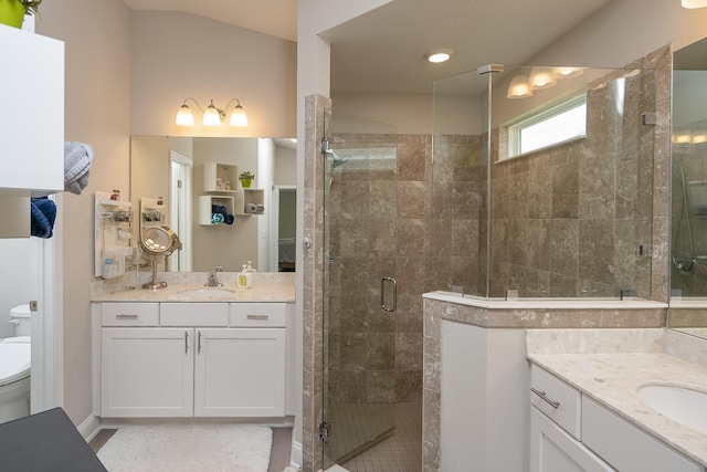 full bathroom featuring a stall shower, two vanities, a sink, and toilet