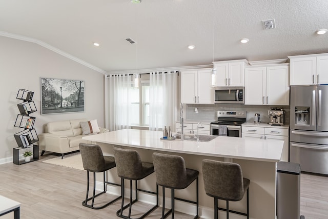 kitchen with visible vents, white cabinetry, vaulted ceiling, appliances with stainless steel finishes, and ornamental molding