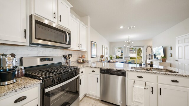 kitchen with stainless steel appliances, sink, white cabinets, an inviting chandelier, and tasteful backsplash