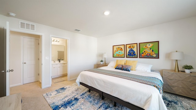 bedroom with ensuite bathroom and light carpet