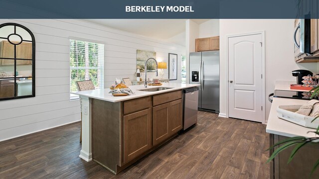 kitchen with a center island with sink, sink, appliances with stainless steel finishes, and dark wood-type flooring