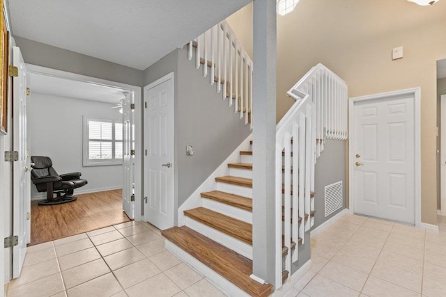 staircase with baseboards, visible vents, and tile patterned flooring