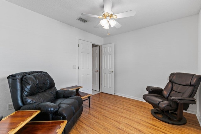 living area featuring baseboards, visible vents, ceiling fan, and light wood-style floors