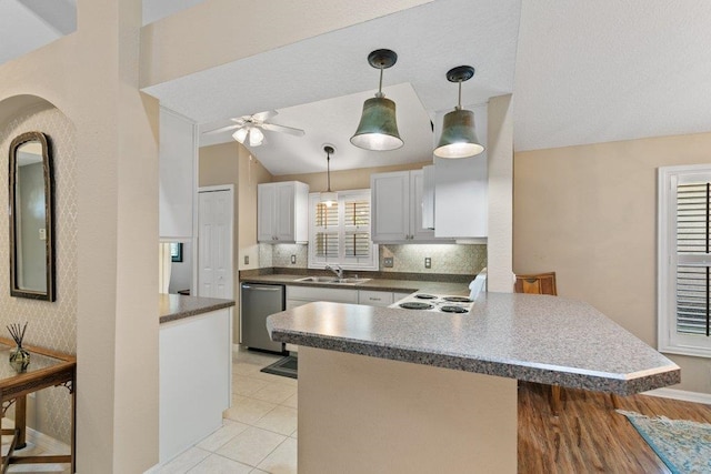 kitchen with a sink, a ceiling fan, decorative light fixtures, a peninsula, and stainless steel dishwasher