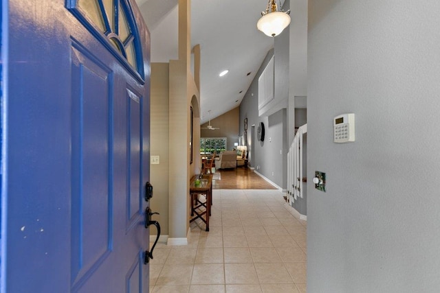 entryway with stairs, baseboards, light tile patterned floors, and lofted ceiling