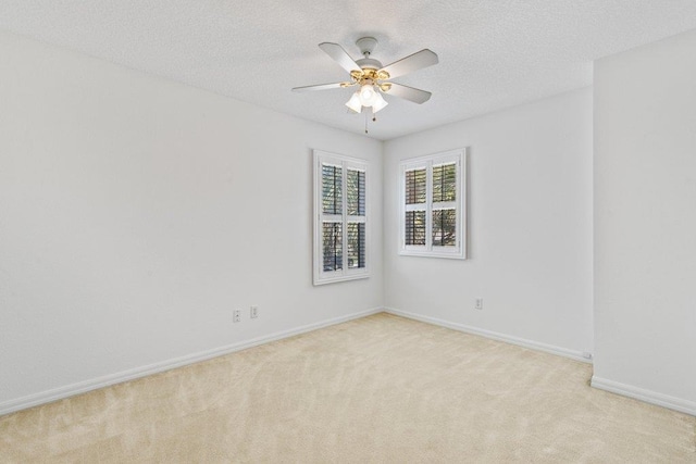 empty room with light colored carpet, a textured ceiling, baseboards, and ceiling fan
