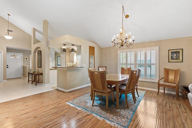 dining area featuring a notable chandelier, vaulted ceiling, baseboards, and light wood-type flooring