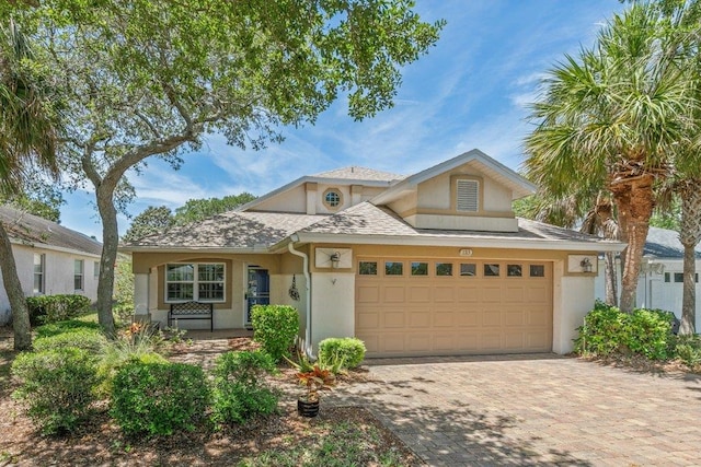 traditional home featuring decorative driveway, an attached garage, and stucco siding