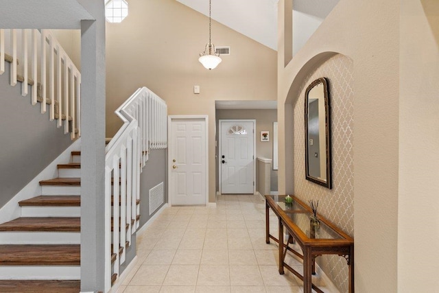 foyer with visible vents, stairs, baseboards, high vaulted ceiling, and light tile patterned floors